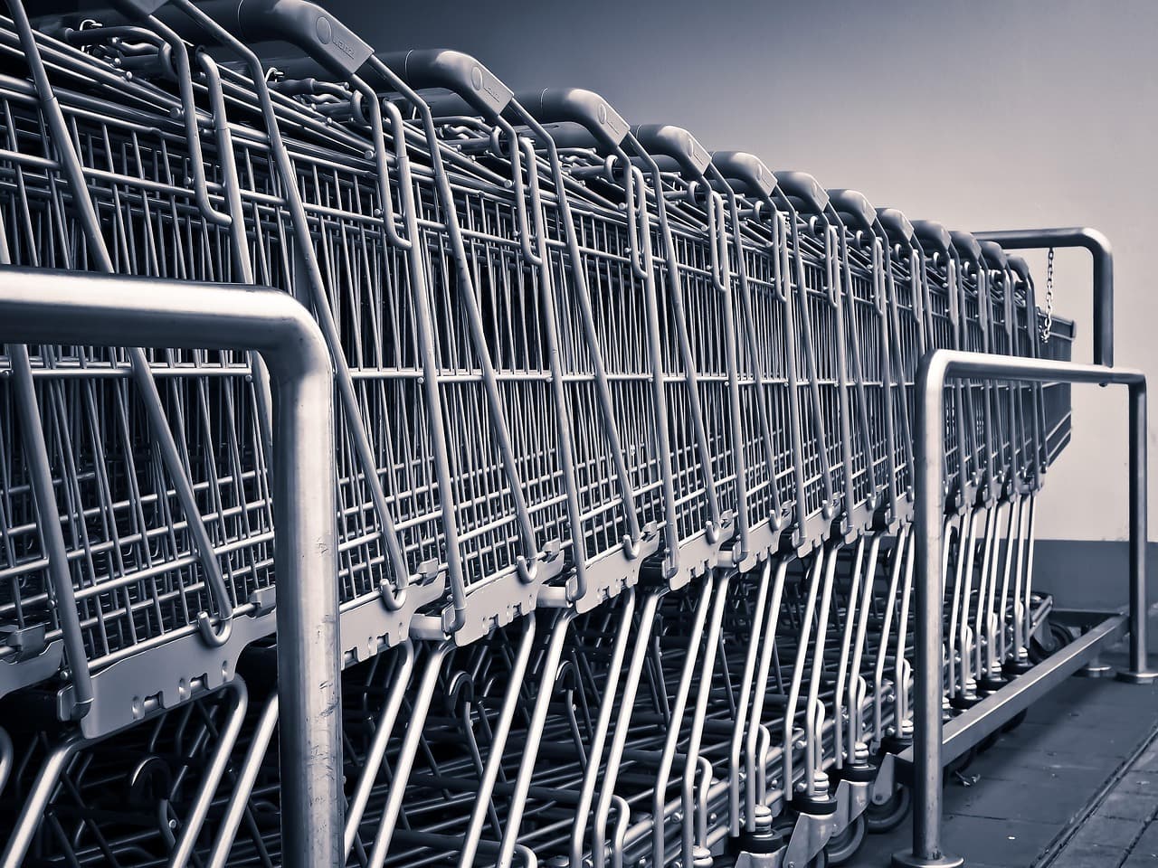 A row of empty metal shopping carts nested together outside a big-box retail store, representing the high-volume, low-price retail model at the center of Walmart's business.