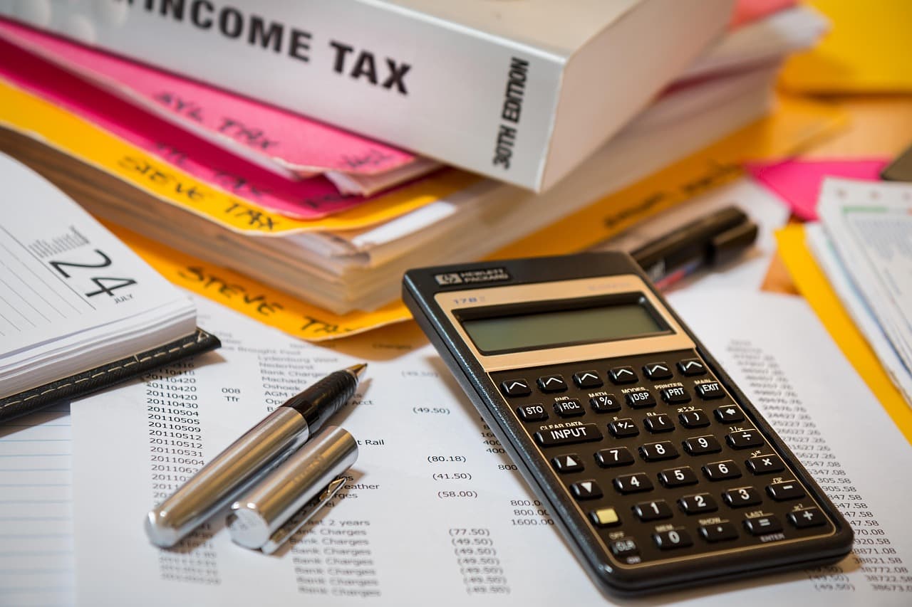 A calculator resting on top of tax documents and financial paperwork, representing the tax-preparation software at the center of Intuit's business