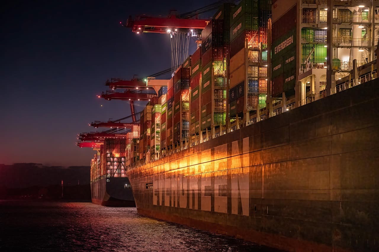 Stacked shipping containers at a cargo port, representing the cross-border freight now caught in the U.S.-Canada tariff dispute.