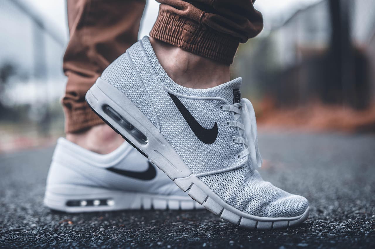 Close-up of a person's feet wearing white Nike athletic sneakers, representing the athletic footwear retail sector at the center of Nike's business
