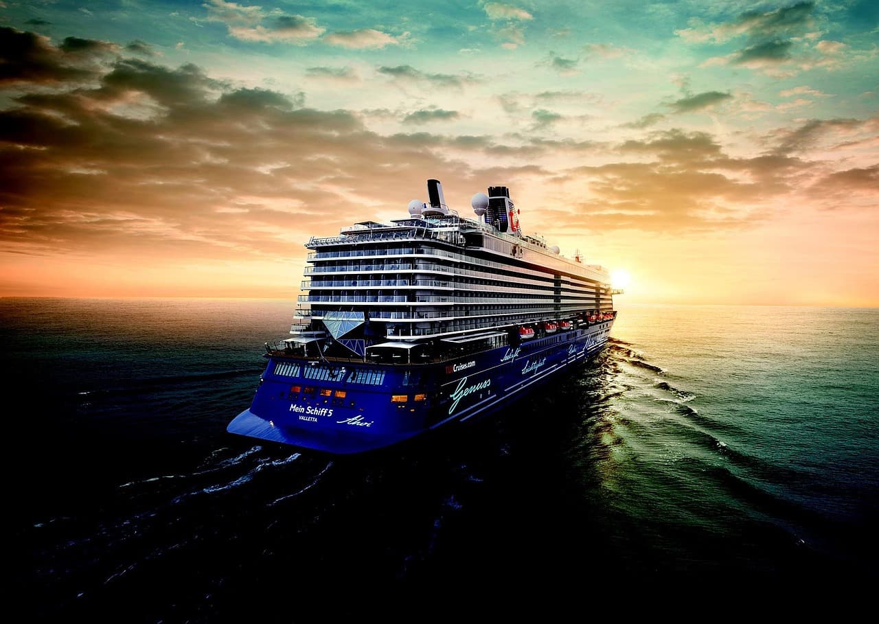A large white cruise ship viewed from the water, representing the major cruise line operators at the center of the sector's current sell-off.